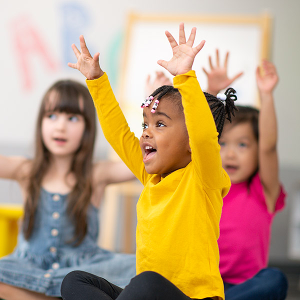 preschoolers sitting with arms raised